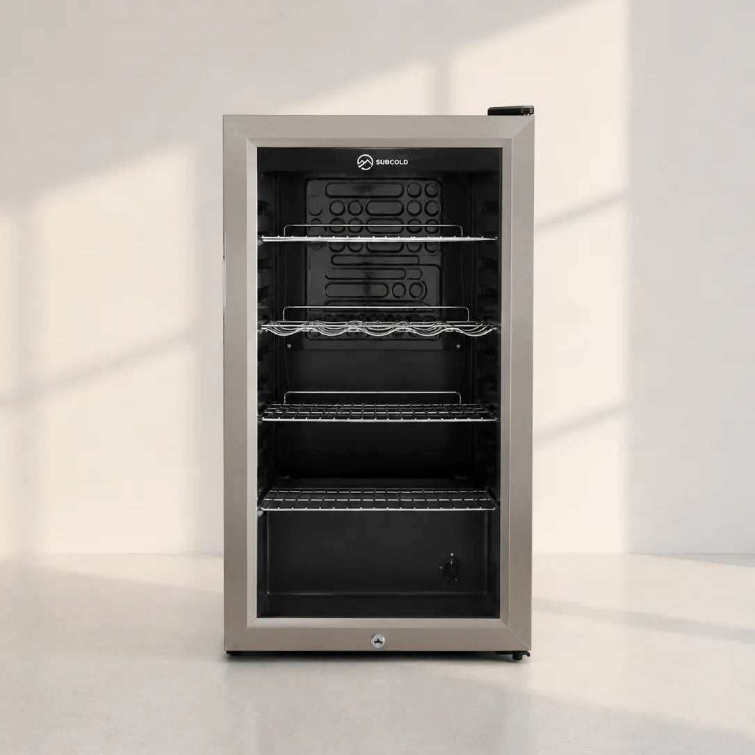 Image of A single-door undercounter beverage refrigerator with a brushed stainless steel exterior and a black glass door, shown on a light gray floor against a white wall with soft window shadows.