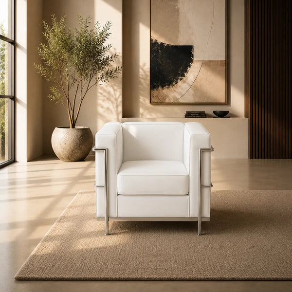 A modern white leather armchair with polished steel side rails and legs, positioned in a minimalist room with warm sunlight casting windowpane shadows on the beige wall and floor.
