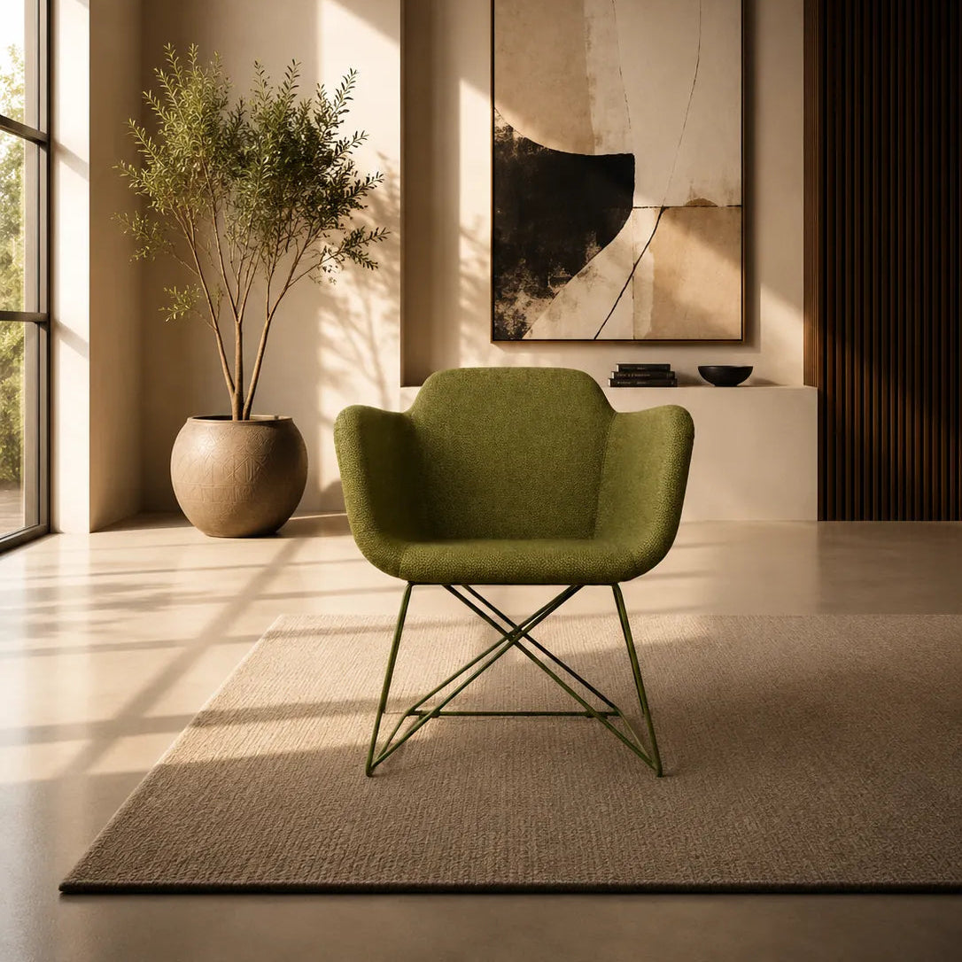 Image of A modern olive green upholstered armchair with thin metal legs sits on a textured beige rug in a sunlit minimalist interior. A large potted plant, abstract wall art, and warm ambient lighting are visible in the background.