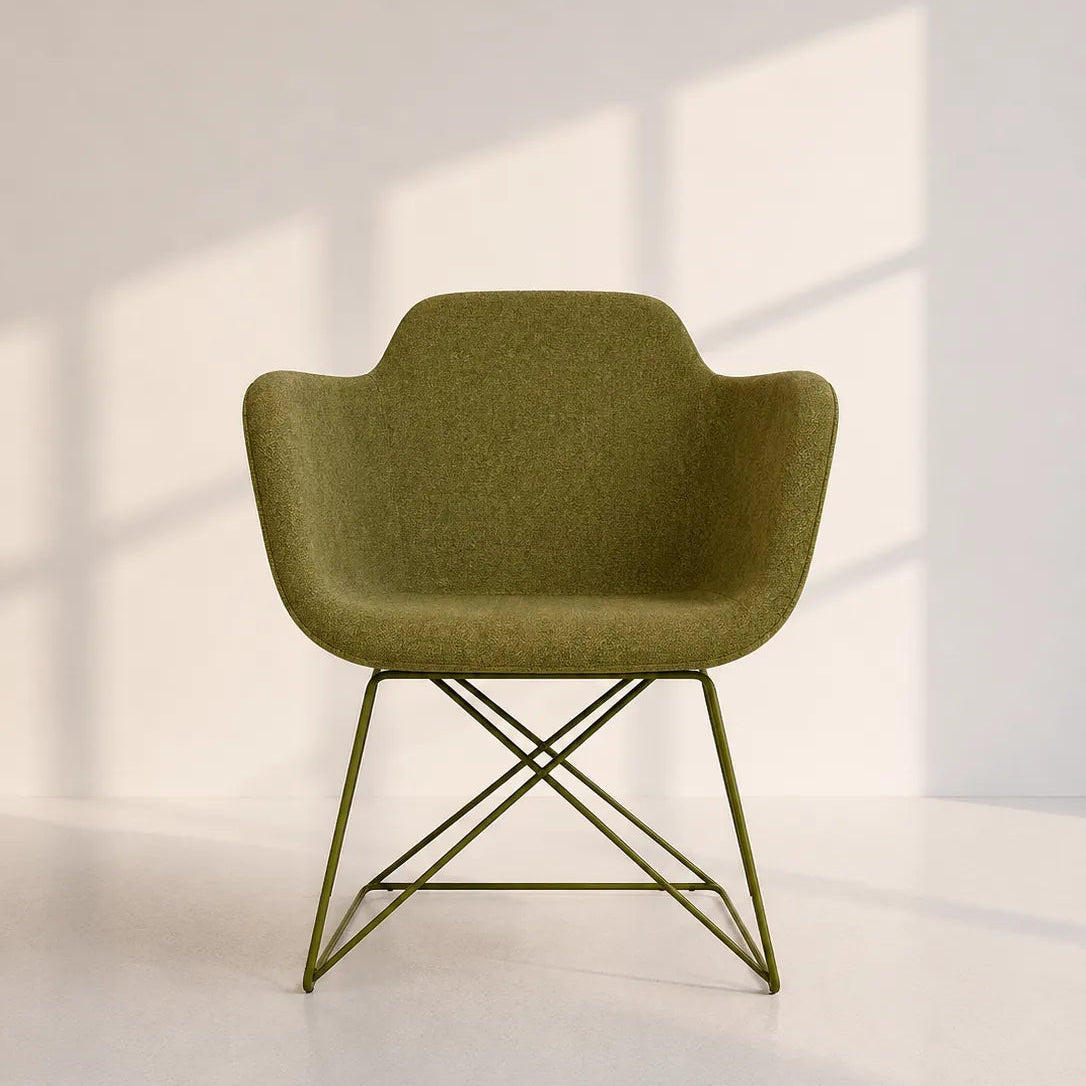 An olive green molded plastic armchair with a thin metal wire frame, set against a minimalist off-white wall with soft window shadow projections.