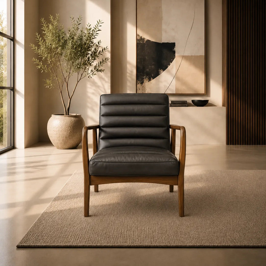 A modern black leather armchair with a wooden frame sits on a textured beige rug in a minimalist, warm-toned interior room with a potted plant and abstract wall art.
