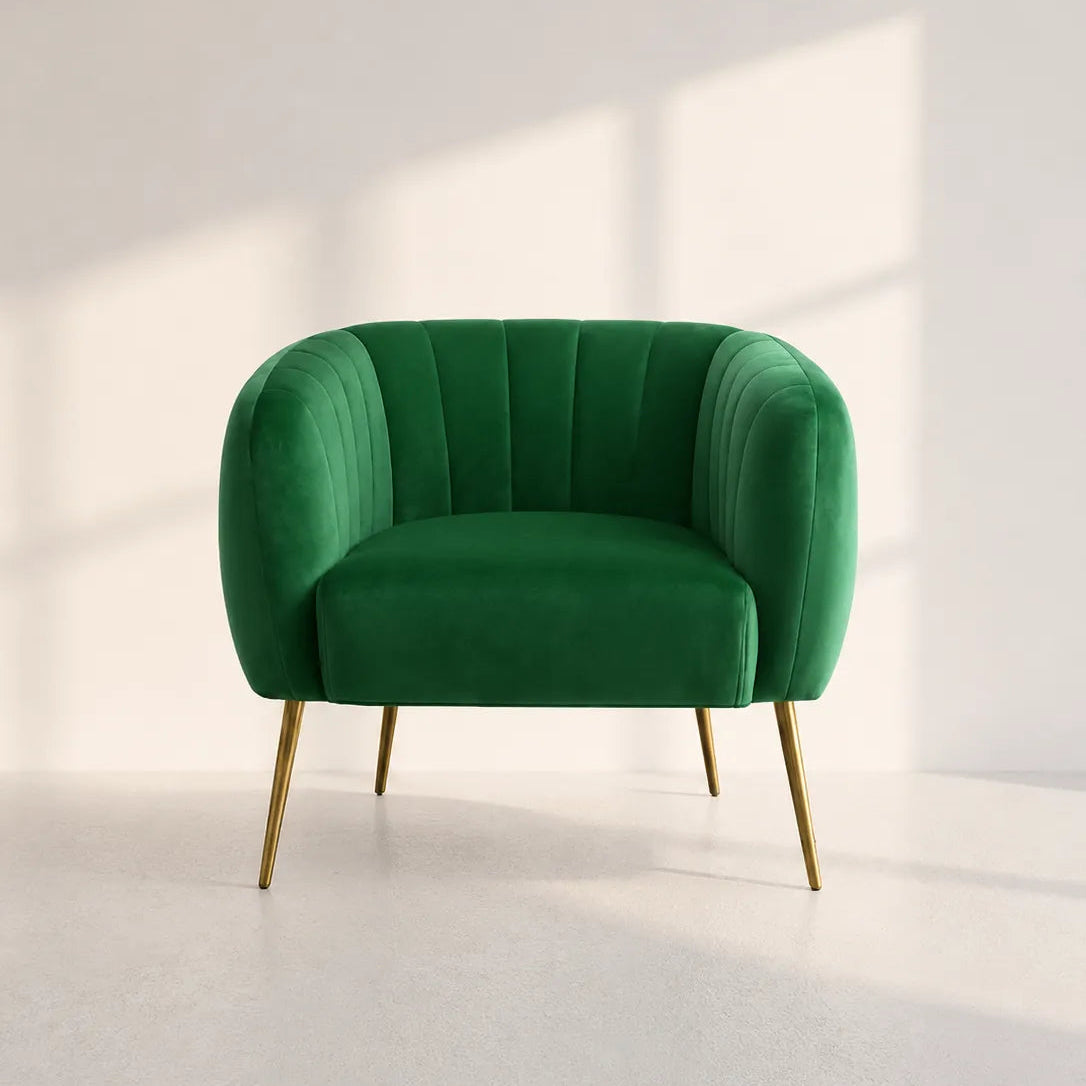 Image of A modern green velvet armchair with gold metal legs, set against a minimalist white wall with soft window shadow light.