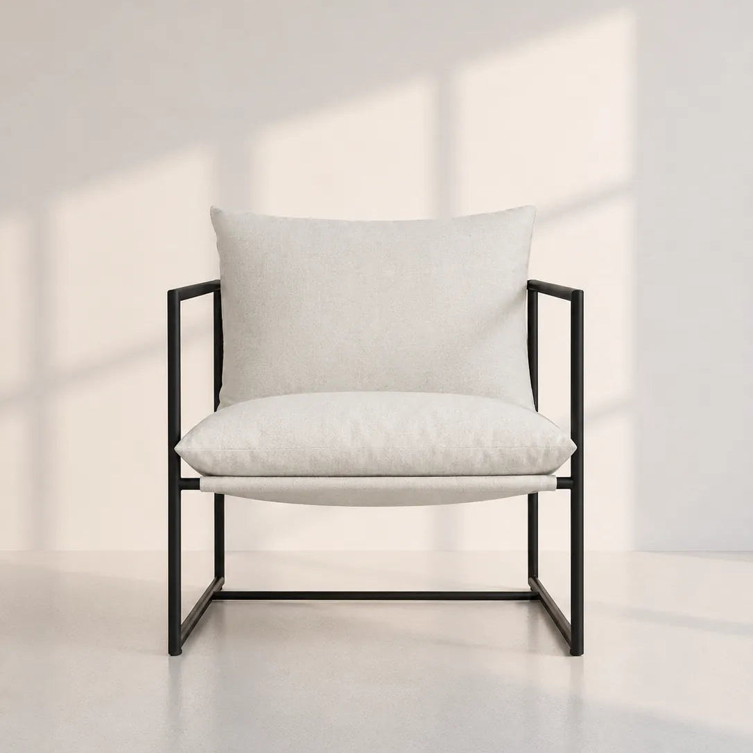 Image of A modern accent chair with a black metal frame and light beige textured cushions, set against a minimalist off-white wall with soft window shadow patterns.