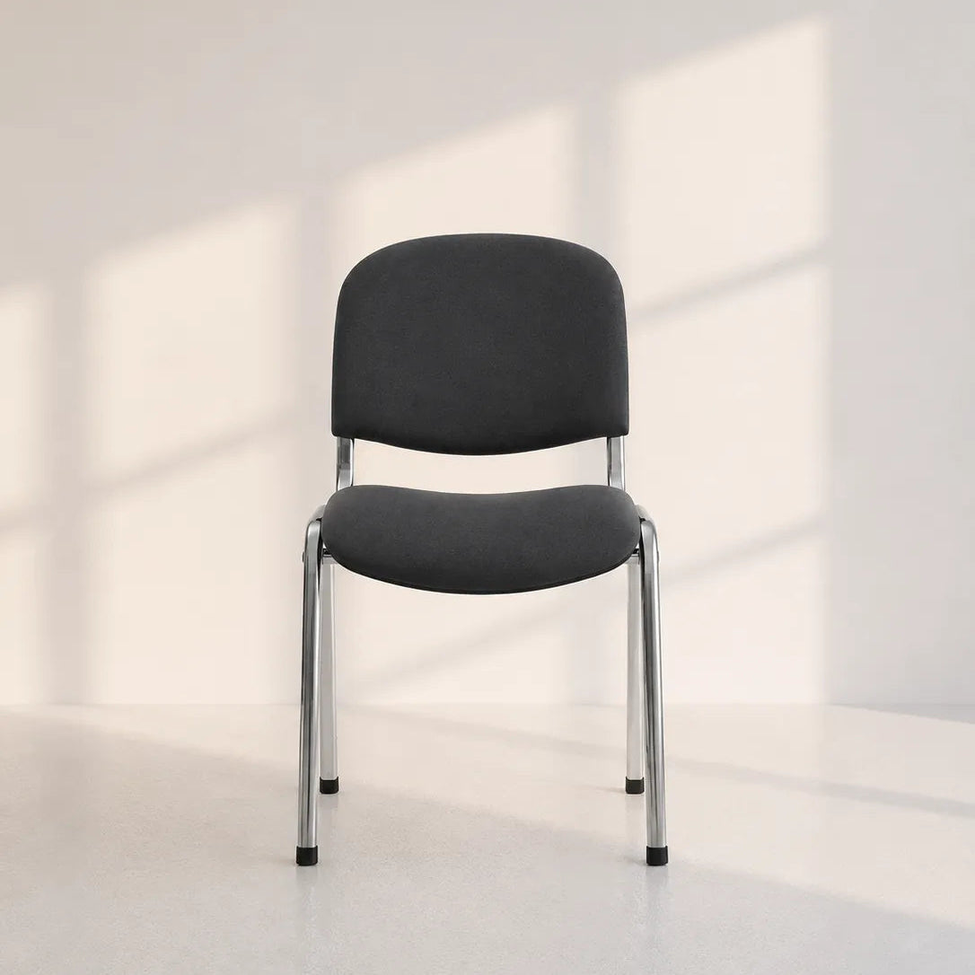 Image of A modern black upholstered chair with a curved backrest and slim silver metal legs, positioned in a minimalist room with soft window-box shadows cast on a light gray wall and floor.