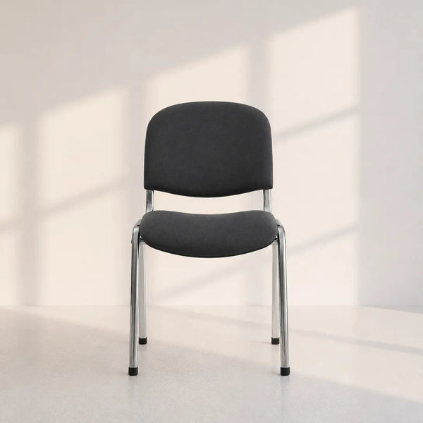 A modern black upholstered chair with a curved backrest and slim silver metal legs, positioned in a minimalist room with soft window-box shadows cast on a light gray wall and floor.