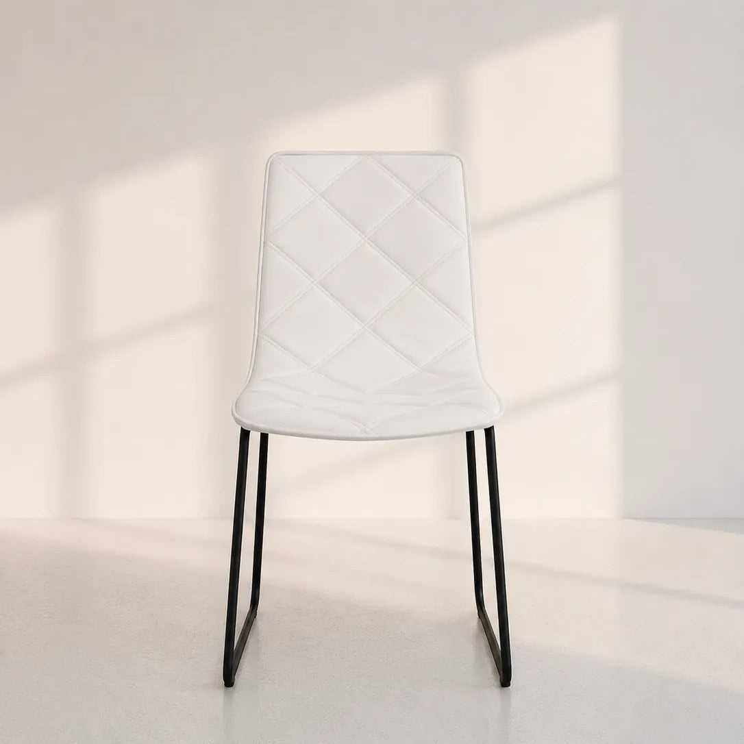 Image of A modern white upholstered dining chair with a diamond-quilted backrest and slim black metal legs, set against a minimalist white wall with soft window shadow patterns.