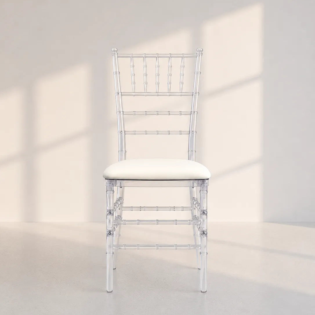 Image of A white Chiavi-style chair with a white upholstered seat cushion, photographed in a minimalist white room with soft window-shadow lighting.