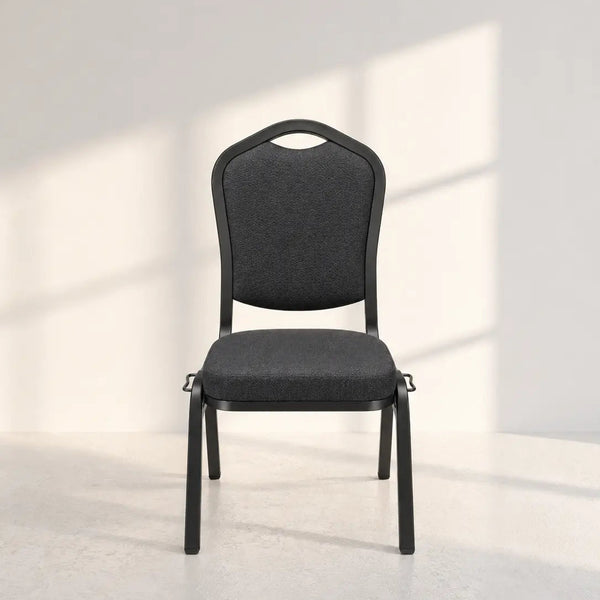 A modern black metal conference chair with a dark gray upholstered seat and backrest, set against a minimalist white wall with soft window shadow patterns.