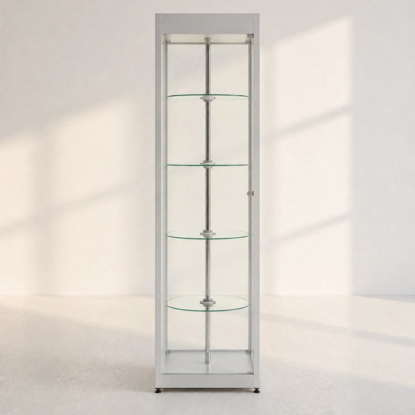 A tall, narrow white glass display cabinet with four glass shelves and a side door, shown in a minimalist white room with soft window shadows.