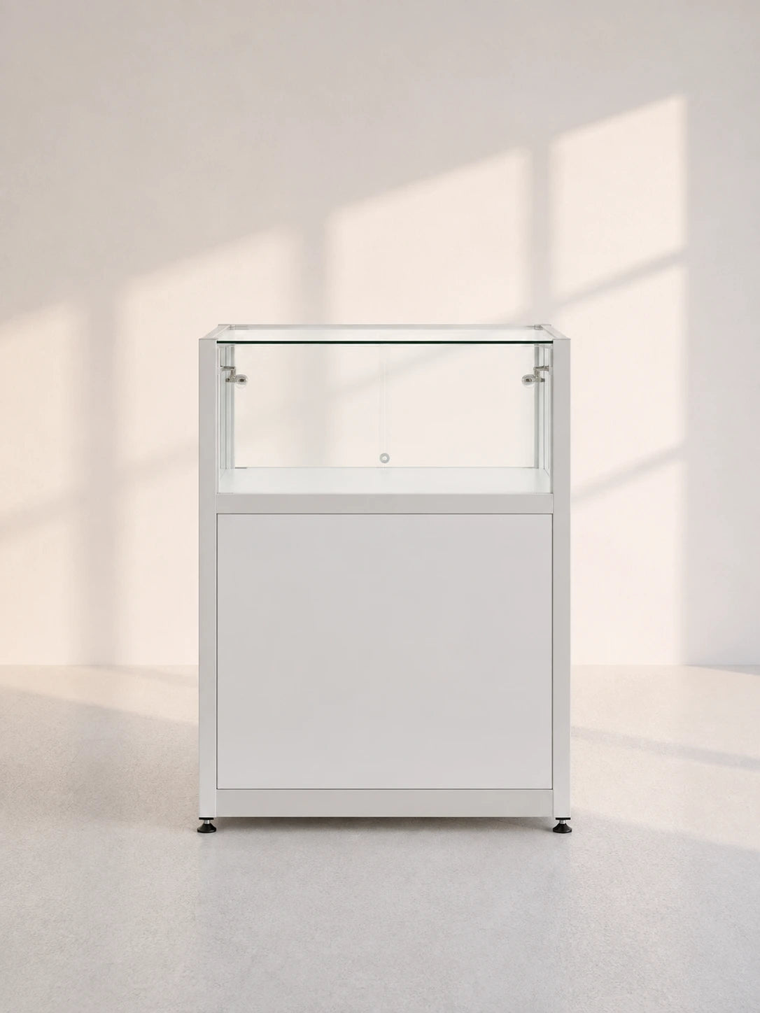 Image of A modern white display cabinet with a glass top showcase section and a lower cabinet door, set against a minimalist light gray wall with soft window shadow projections.