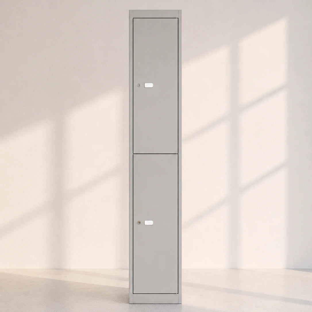 Image of A tall, narrow gray metal storage cabinet with two doors and small lock areas, standing against a light wall with soft window-shadow patterns on the floor.