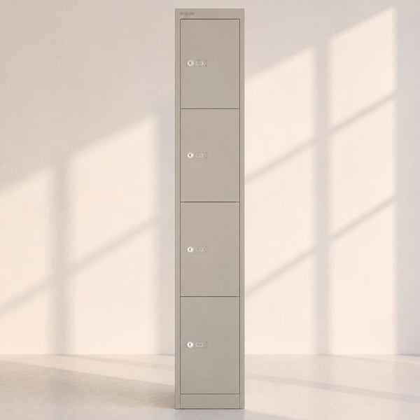A tall, narrow four-door metal locker in a warm gray or taupe color, standing against a minimalist off-white wall with soft window shadow patterns cast across it.