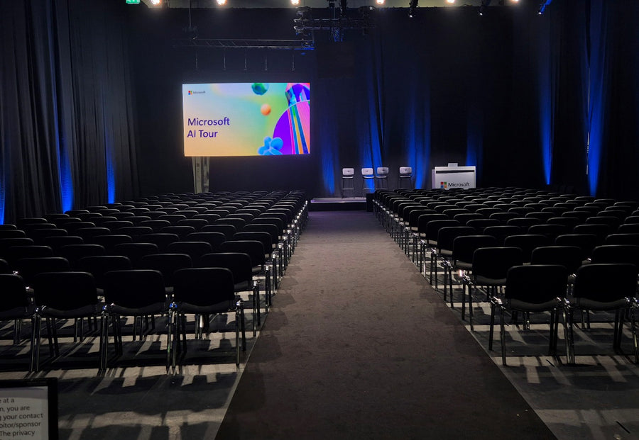 Conference hall set with rows of black conference chairs for the Microsoft AI Tour