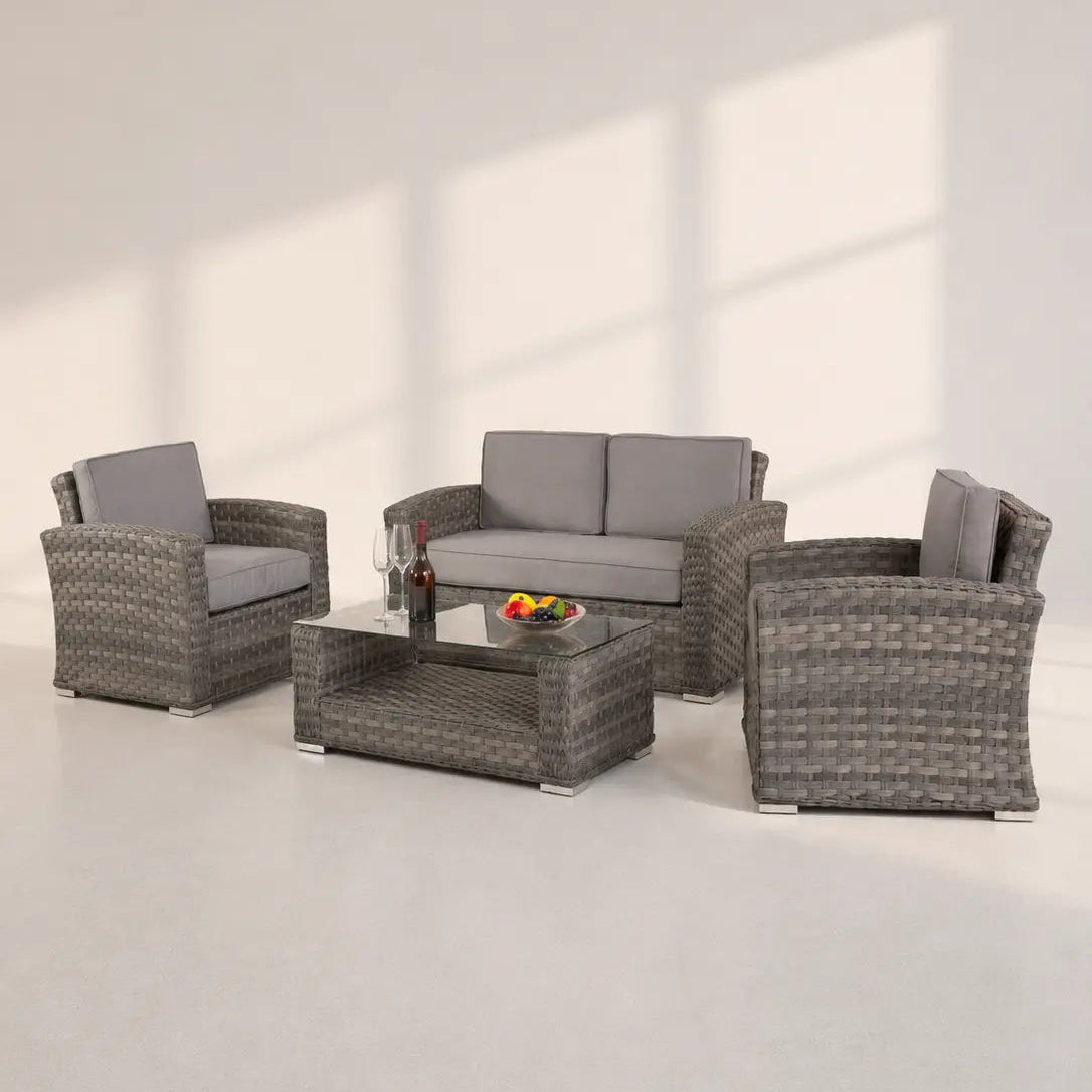 Image of A 4-piece outdoor wicker furniture set with a loveseat, two armchairs, and a coffee table, featuring gray woven frames and light gray cushions, set against a minimalist off-white background with window shadow projections.