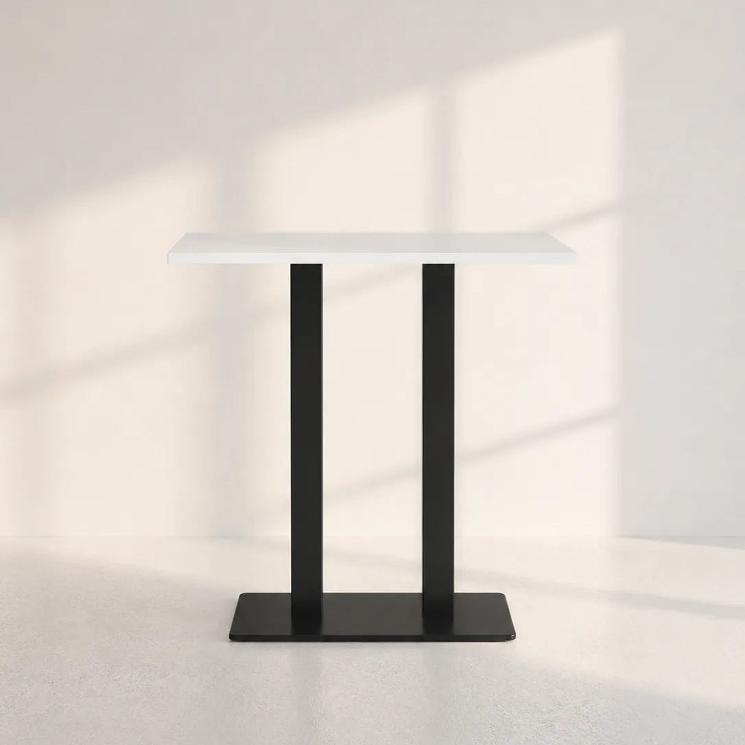 Image of A modern minimalist side table with a white rectangular top and two black metal legs forming a square base, set against a warm off-white wall with soft window shadow patterns.