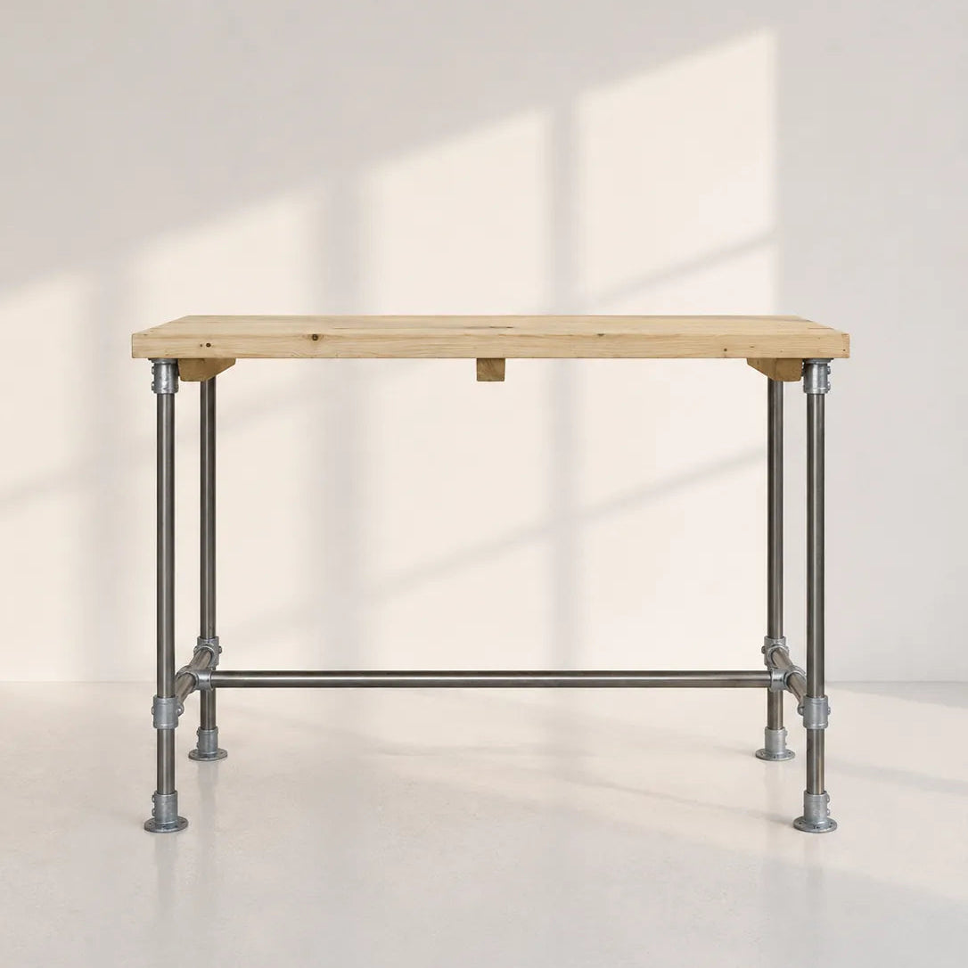 Image of A rectangular workbench with a light natural wood top and a silver metal industrial pipe frame, set against a white wall with soft window shadow patterns.