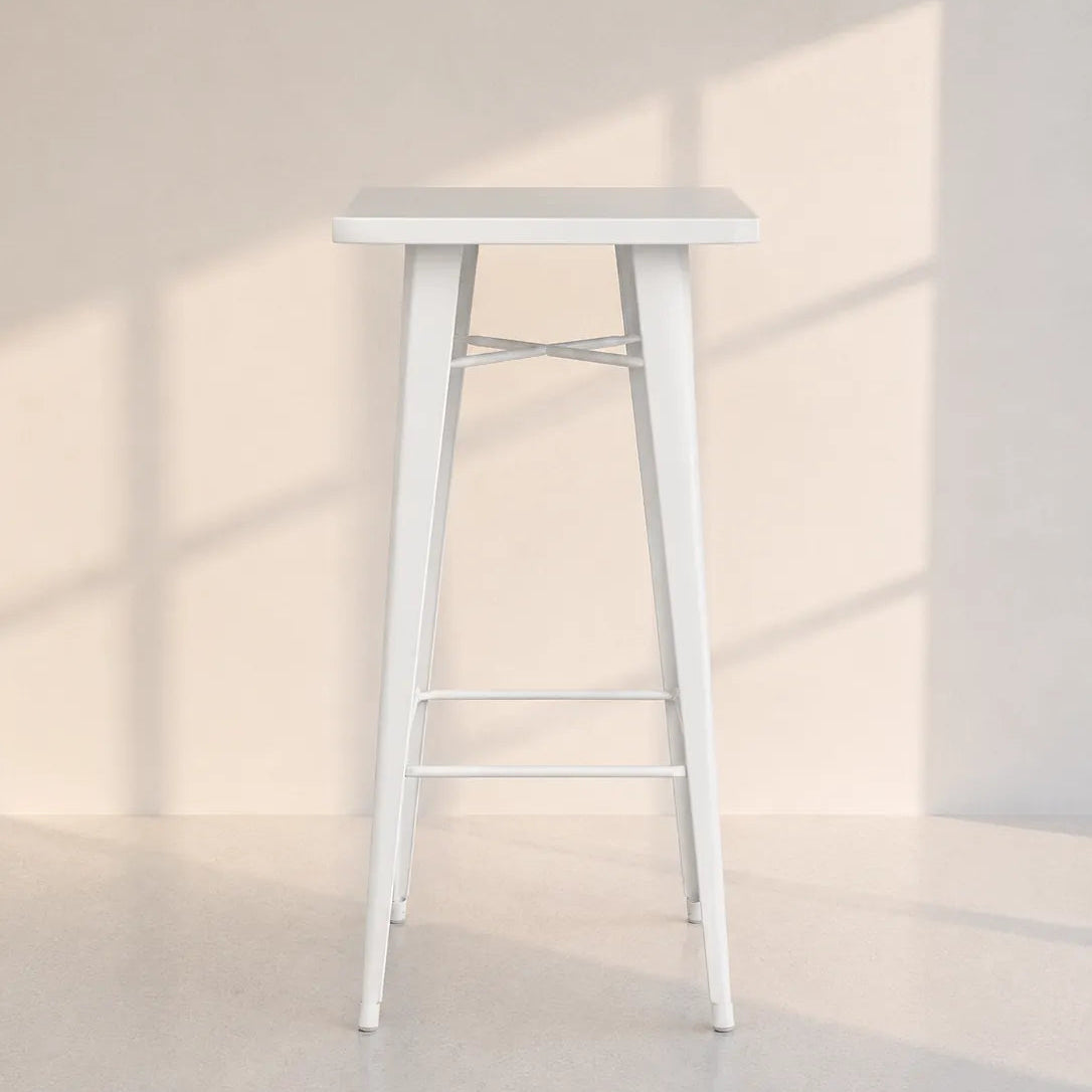 A white metal bar stool with a square seat, four tapered legs, and two footrests, set against a minimalist beige wall with soft window shadow patterns.