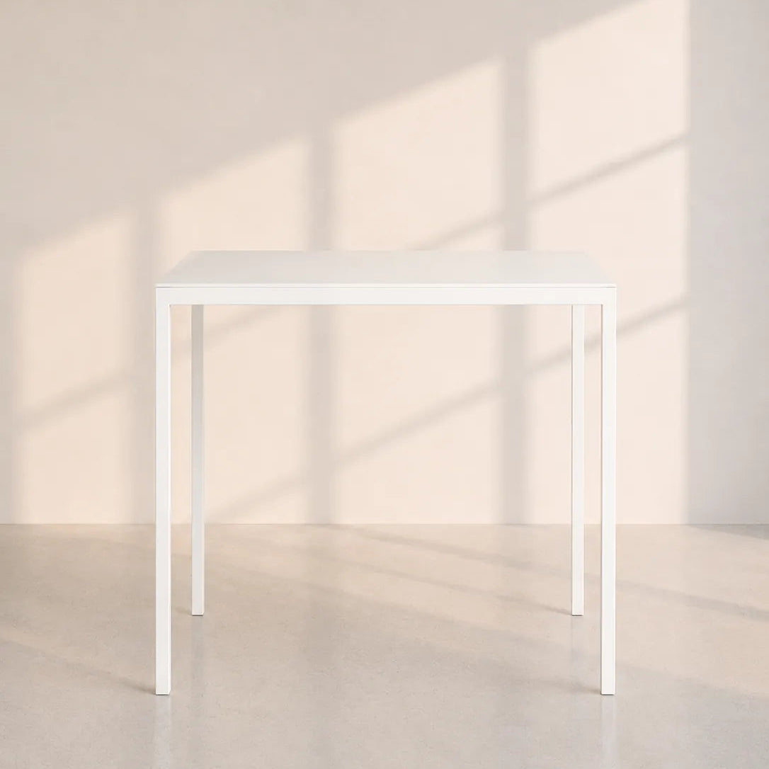 Image of A minimalist white rectangular table with slim legs, set against a warm beige wall with soft window shadow patterns.