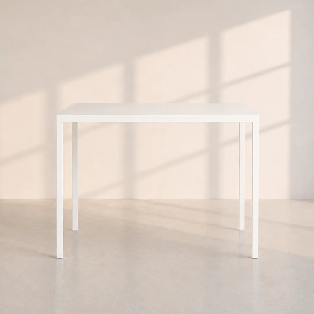 Image of A minimalist white rectangular table with slim legs, set against a warm beige wall with soft window shadow patterns.