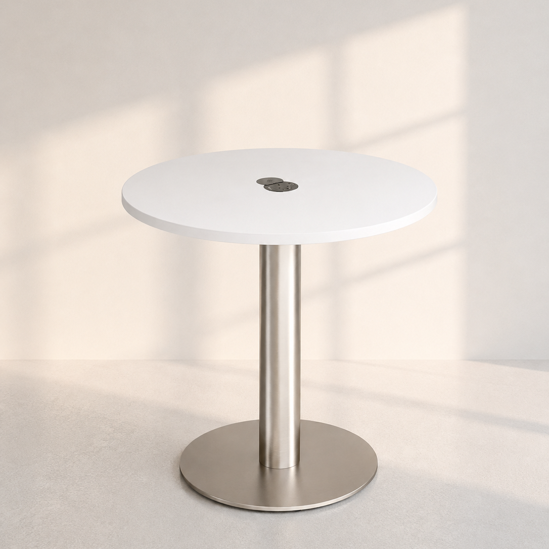 Image of A modern round table with a white top and a brushed silver metal pedestal base, set against a minimalist light beige wall with soft window shadow patterns.