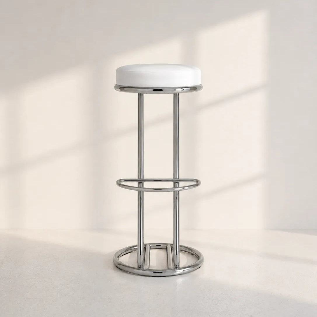 Image of A modern bar stool with a white circular cushioned seat and a polished chrome metal frame, set against a minimalist off-white background with soft window shadow projections.