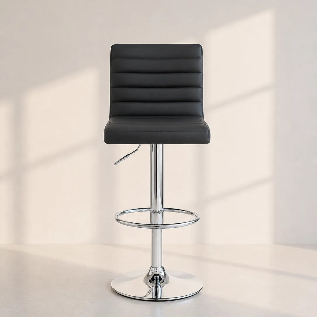 Image of A modern black faux-leather swivel bar stool with a chrome-plated metal base, featuring a circular footrest ring and a high backrest, set against a minimalist off-white background with soft window shadow projections.