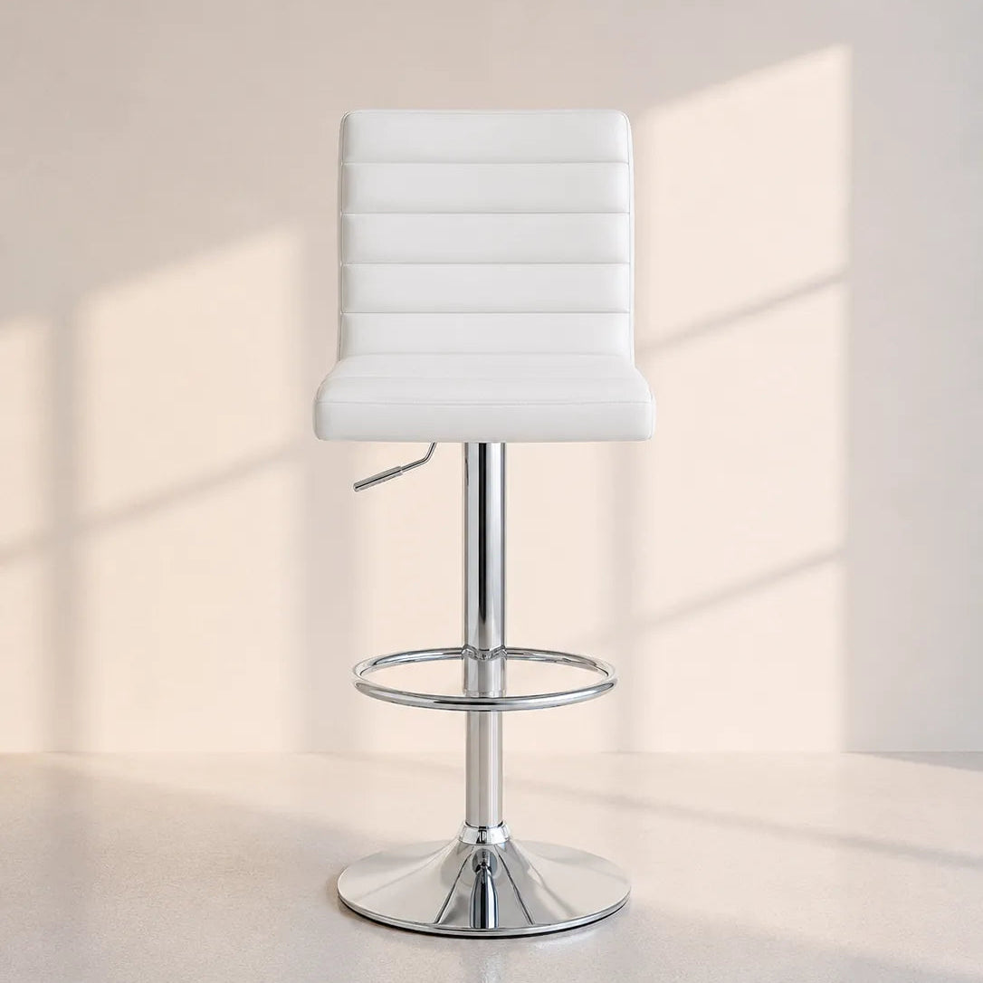 Image of A modern white upholstered bar stool with a chrome metal pedestal base, footrest ring, and swivel seat, shown in a minimalist studio setting with soft window-shadow lighting.