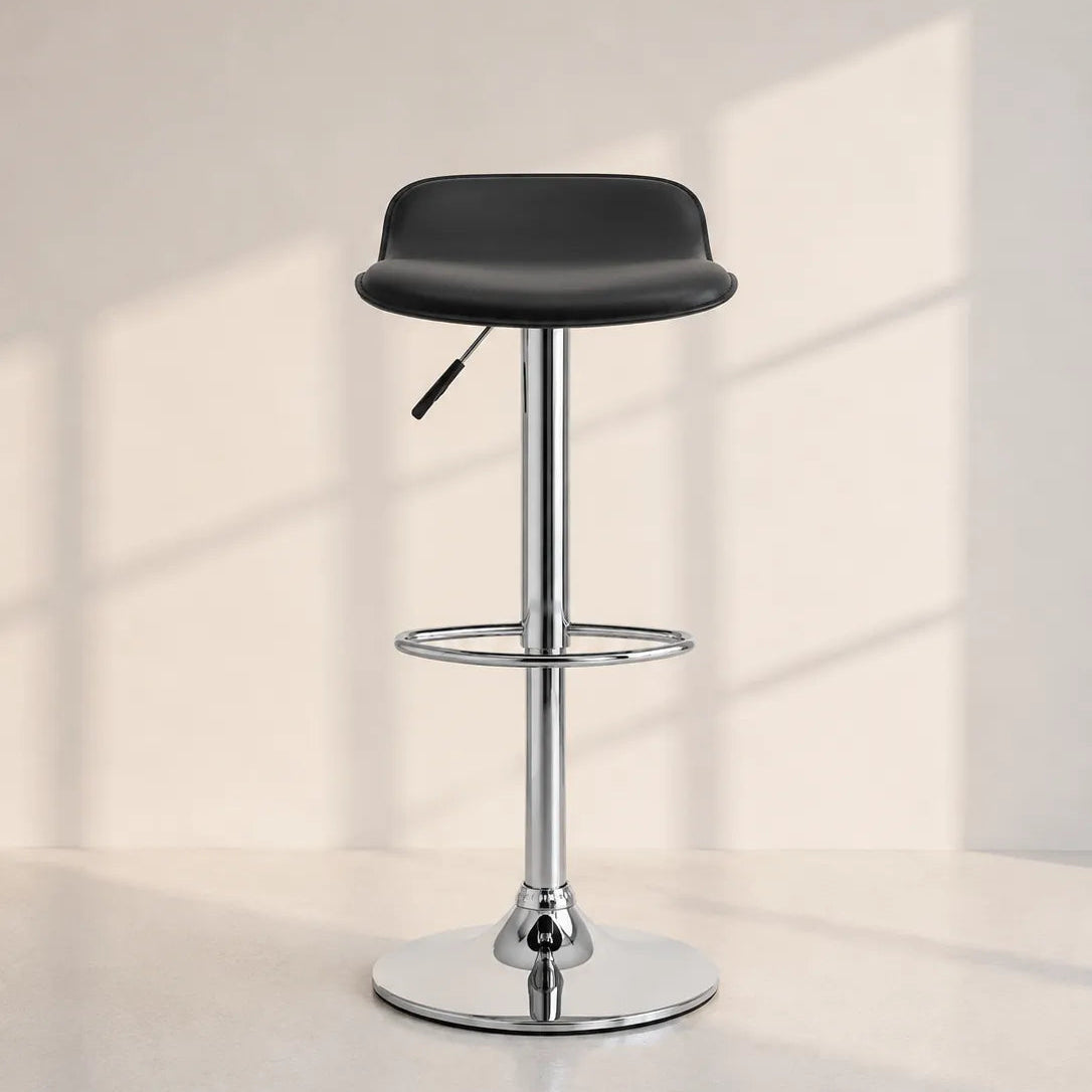 A modern adjustable bar stool with a black upholstered seat, chrome metal pedestal base, and footrest, set against a minimalist beige wall with soft window shadow patterns.