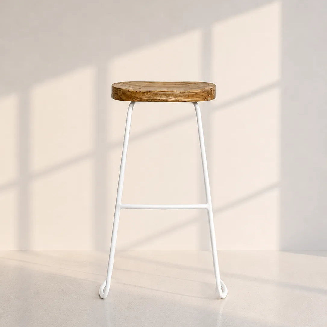 A modern bar stool with a round, rustic brown wooden seat and a slim white metal frame, set against a minimalist beige wall with soft window shadow patterns.