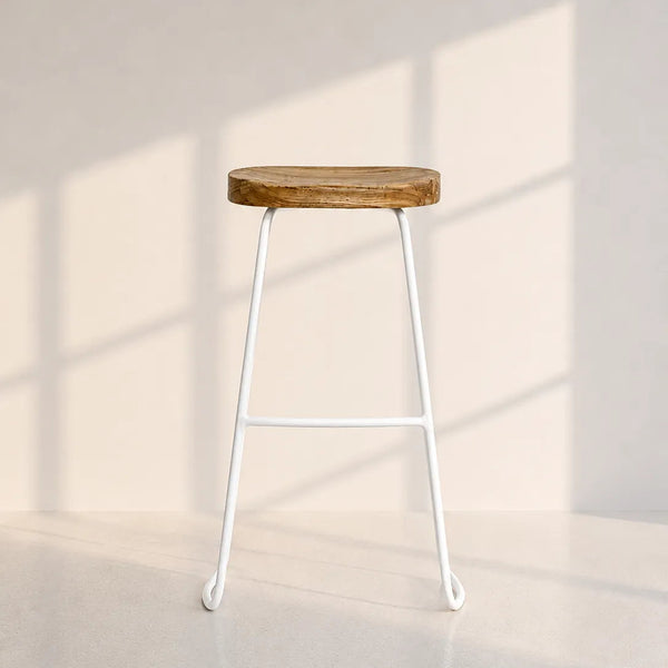 A modern bar stool with a round, rustic brown wooden seat and a slim white metal frame, set against a minimalist beige wall with soft window shadow patterns.