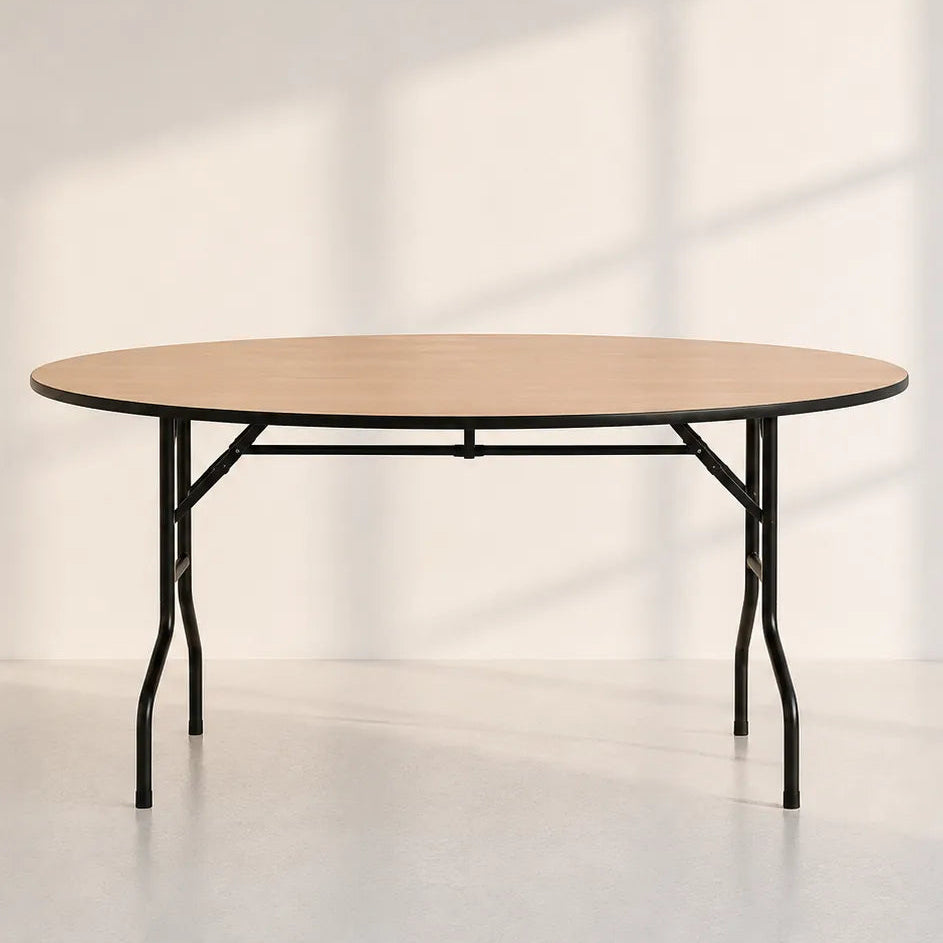 Image of A round folding table with a light natural wood top and black metal legs, set against a minimalist off-white wall with soft window shadow patterns.